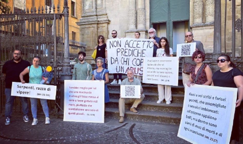 Fedeli escono dalla chiesa, cartelli contro i silenzi della Curia sugli abusi